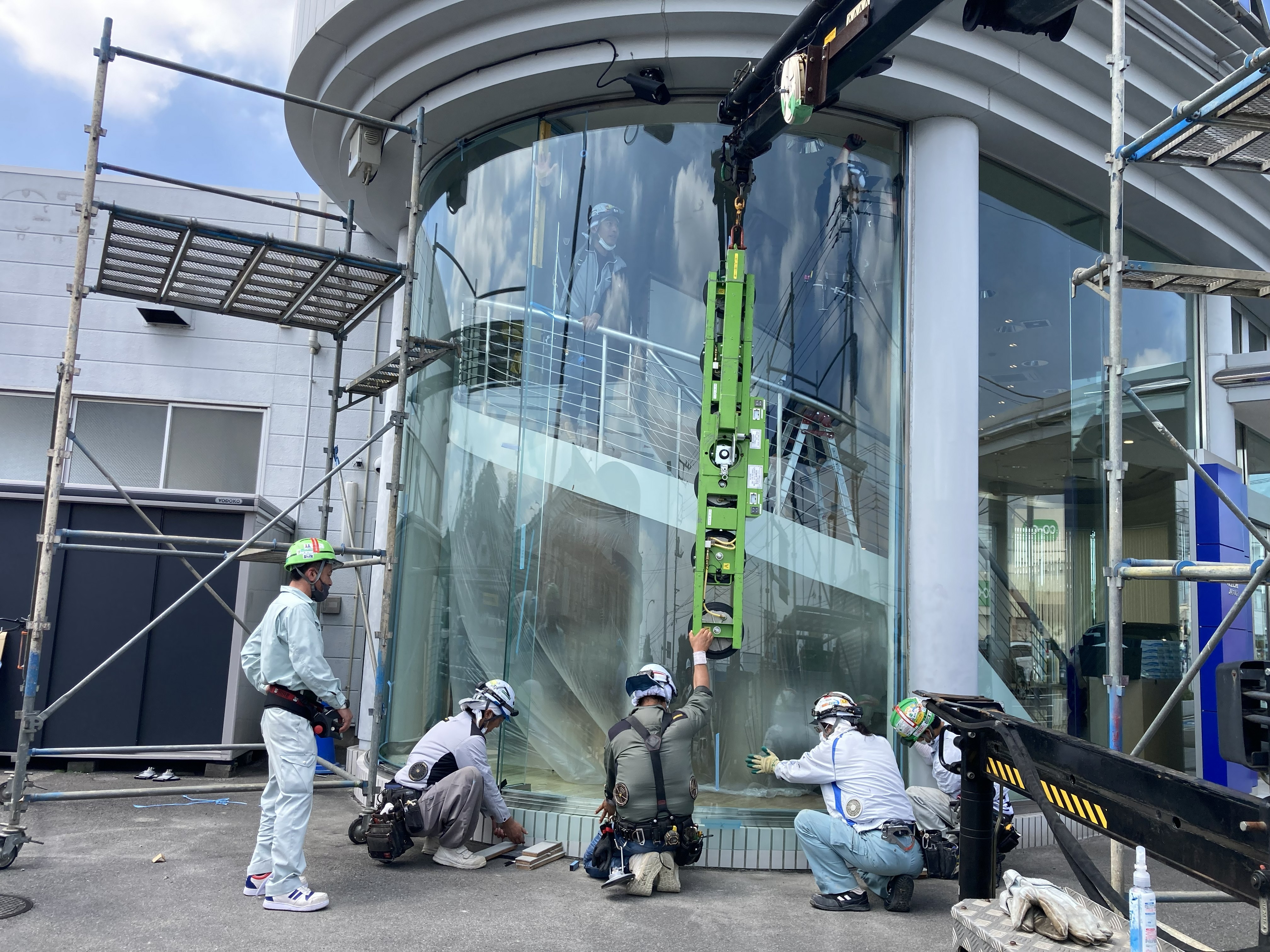 クレーンを使用して大型曲げガラスを建て込む工程